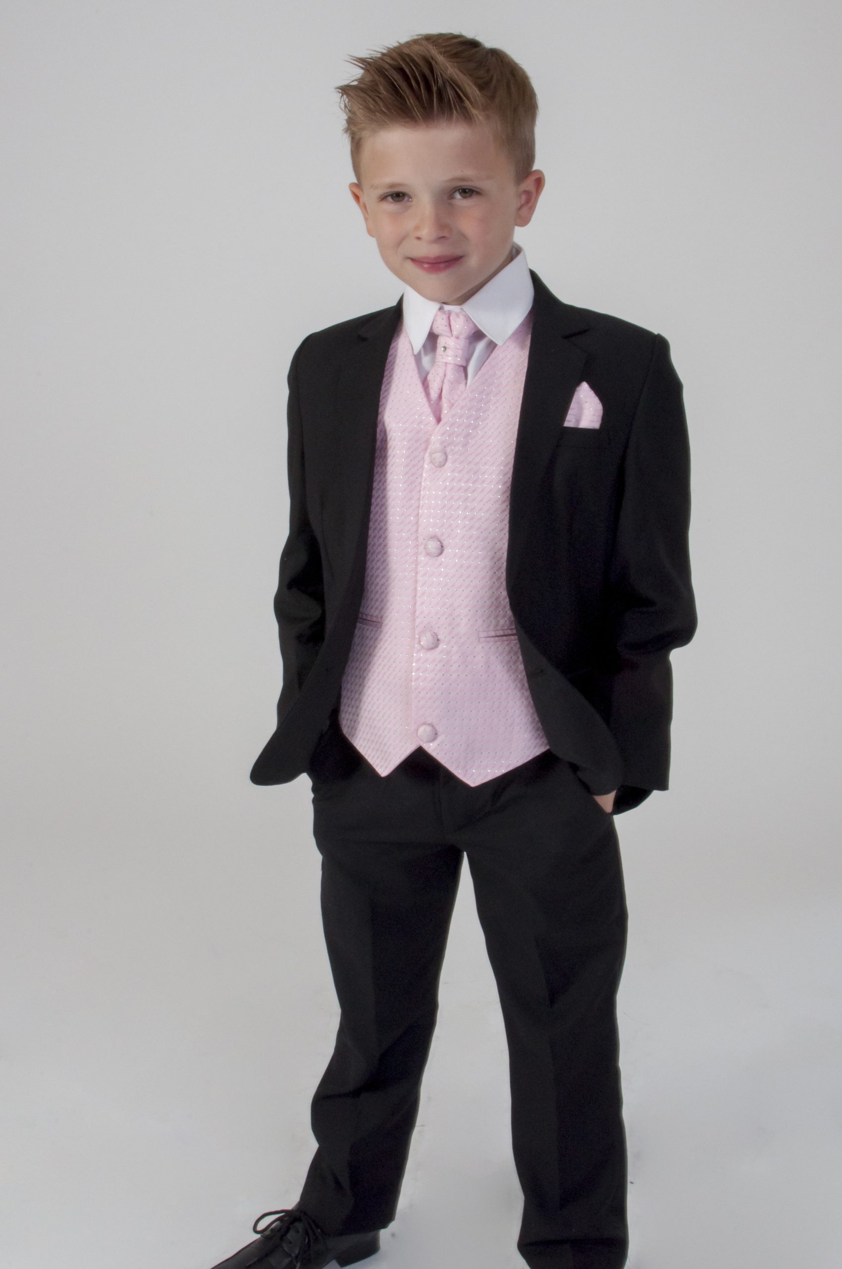 The Christian Boy's 5-piece suit at The Bride Shop in Milton Keynes, featuring a beautiful cameo pink vest and black jacket and trousers, suitable for weddings and formal events for boys